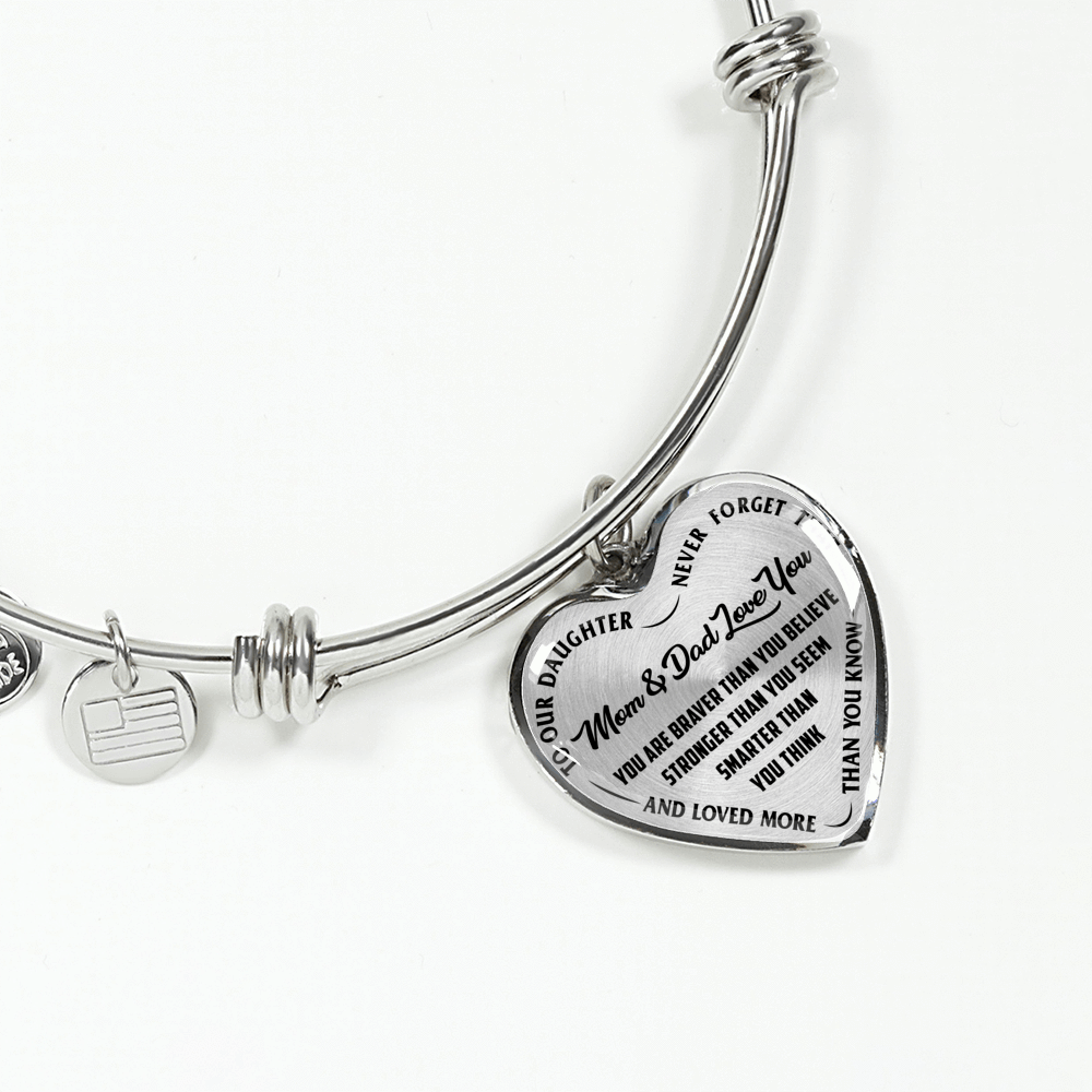 TO OUR DAUGHTER, YOU ARE BRAVER, MOM & DAD LOVE YOU - GOLD AND SILVER FINISHED HEART SHAPED BANGLE BRACELET (BLACK TEXT ON TRANSPARENT)