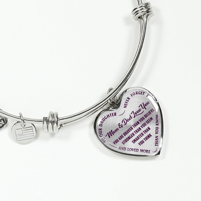 TO OUR DAUGHTER, YOU ARE BRAVER, MOM & DAD LOVE YOU - GOLD AND SILVER FINISHED HEART SHAPED BANGLE BRACELET (PURPLE TEXT ON TRANSPARENT)