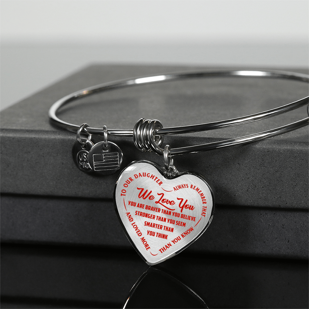 TO OUR DAUGHTER, WE LOVE YOU - SILVER OR GOLD FINISHED HEART SHAPED BANGLE BRACELET (RED ON TRANSPARENT)