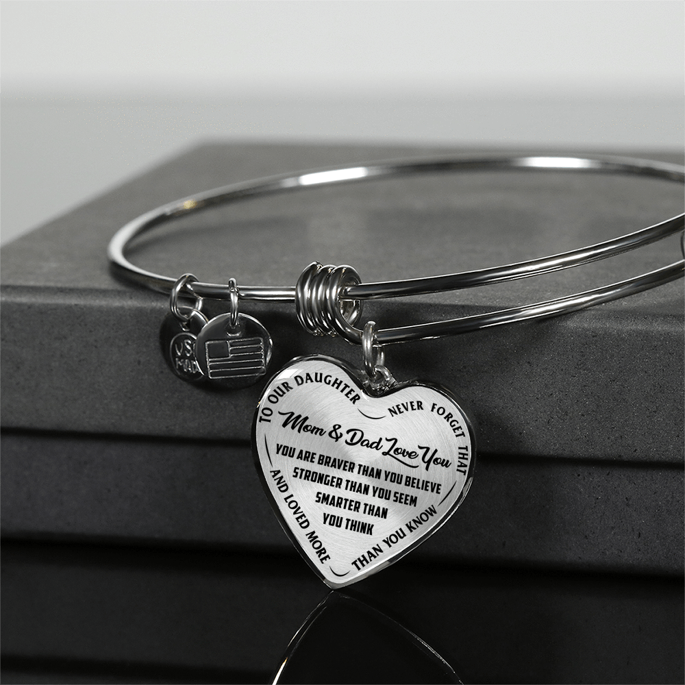 TO OUR DAUGHTER, YOU ARE BRAVER, MOM & DAD LOVE YOU - GOLD AND SILVER FINISHED HEART SHAPED BANGLE BRACELET (BLACK TEXT ON TRANSPARENT)