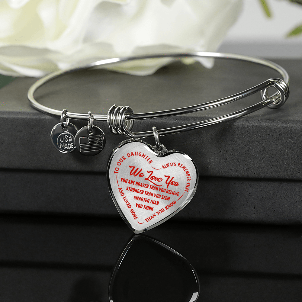 TO OUR DAUGHTER, WE LOVE YOU - SILVER OR GOLD FINISHED HEART SHAPED BANGLE BRACELET (RED ON TRANSPARENT)