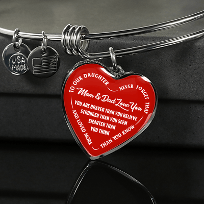 TO OUR DAUGHTER, YOU ARE BRAVER, MOM & DAD LOVE YOU - GOLD AND SILVER FINISHED HEART SHAPED BANGLE BRACELET (WHITE TEXT ON RED)