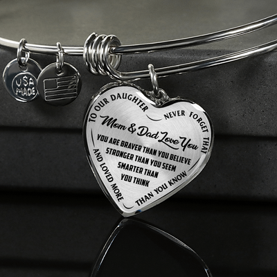 TO OUR DAUGHTER, YOU ARE BRAVER, MOM & DAD LOVE YOU - GOLD AND SILVER FINISHED HEART SHAPED BANGLE BRACELET (BLACK TEXT ON TRANSPARENT)