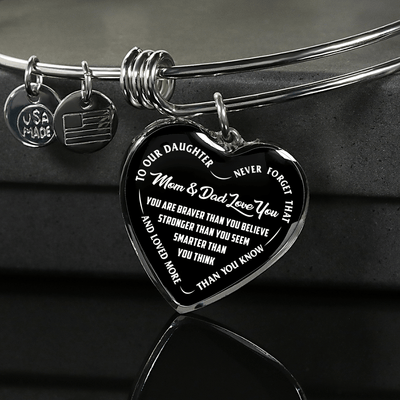 TO OUR DAUGHTER, YOU ARE BRAVER, MOM & DAD LOVE YOU - GOLD AND SILVER FINISHED HEART SHAPED BANGLE BRACELET (WHITE TEXT ON BLACK)