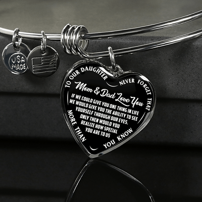 TO OUR DAUGHTER, MOM & DAD LOVE YOU, NEVER FORGET THAT - GOLD AND SILVER FINISHED HEART SHAPED BANGLE BRACELET (WHITE TEXT ON BLACK)