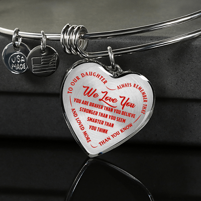 TO OUR DAUGHTER, WE LOVE YOU - SILVER OR GOLD FINISHED HEART SHAPED BANGLE BRACELET (RED ON TRANSPARENT)